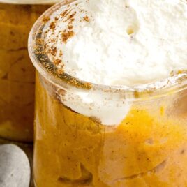 a close up shot of a cup of Pumpkin Pudding topped with whipped cream