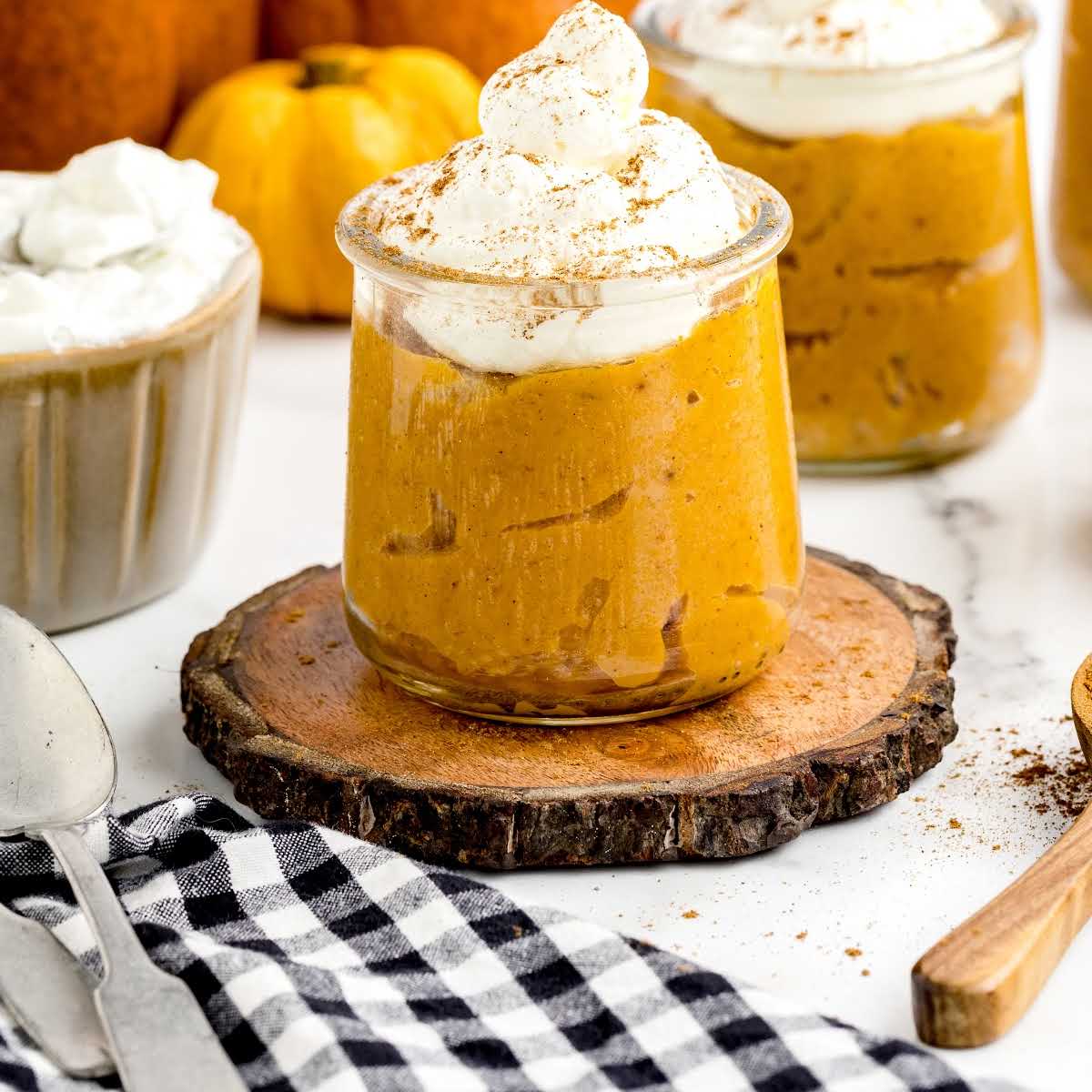 a close up shot of a cup of Pumpkin Pudding topped with whipped cream