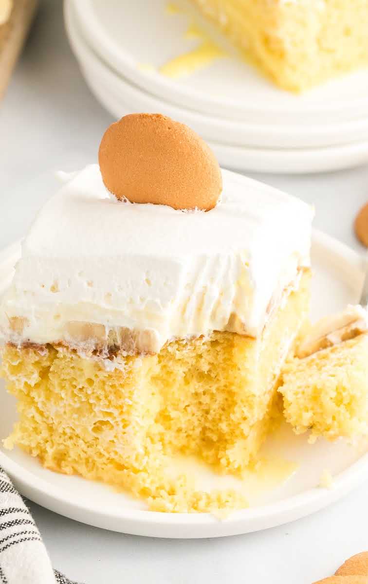 close up shot of a slice of Banana Pudding Cake topped with a vanilla wafer on a plate