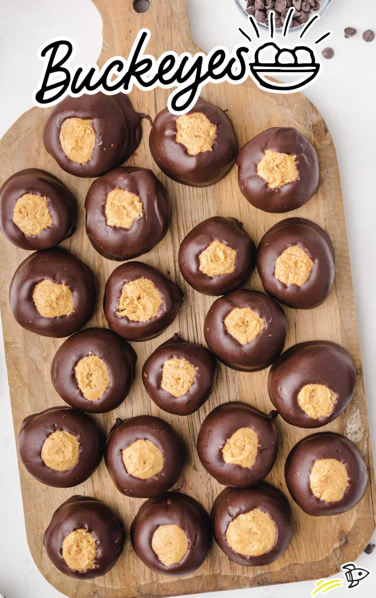 Wooden board topped with chocolate-dipped buckeyes arranged in rows with the peanut butter centers showing.