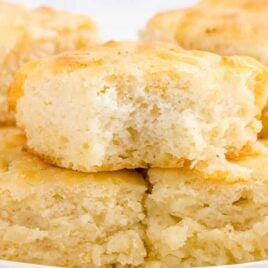 close up overhead shot of Butter Swim Biscuits in a baking dish with a biscuit being picked up with a spatula