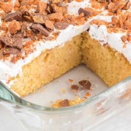 close up shot of Butterfinger Cake garnished with butterfinger candy bits in a baking dish