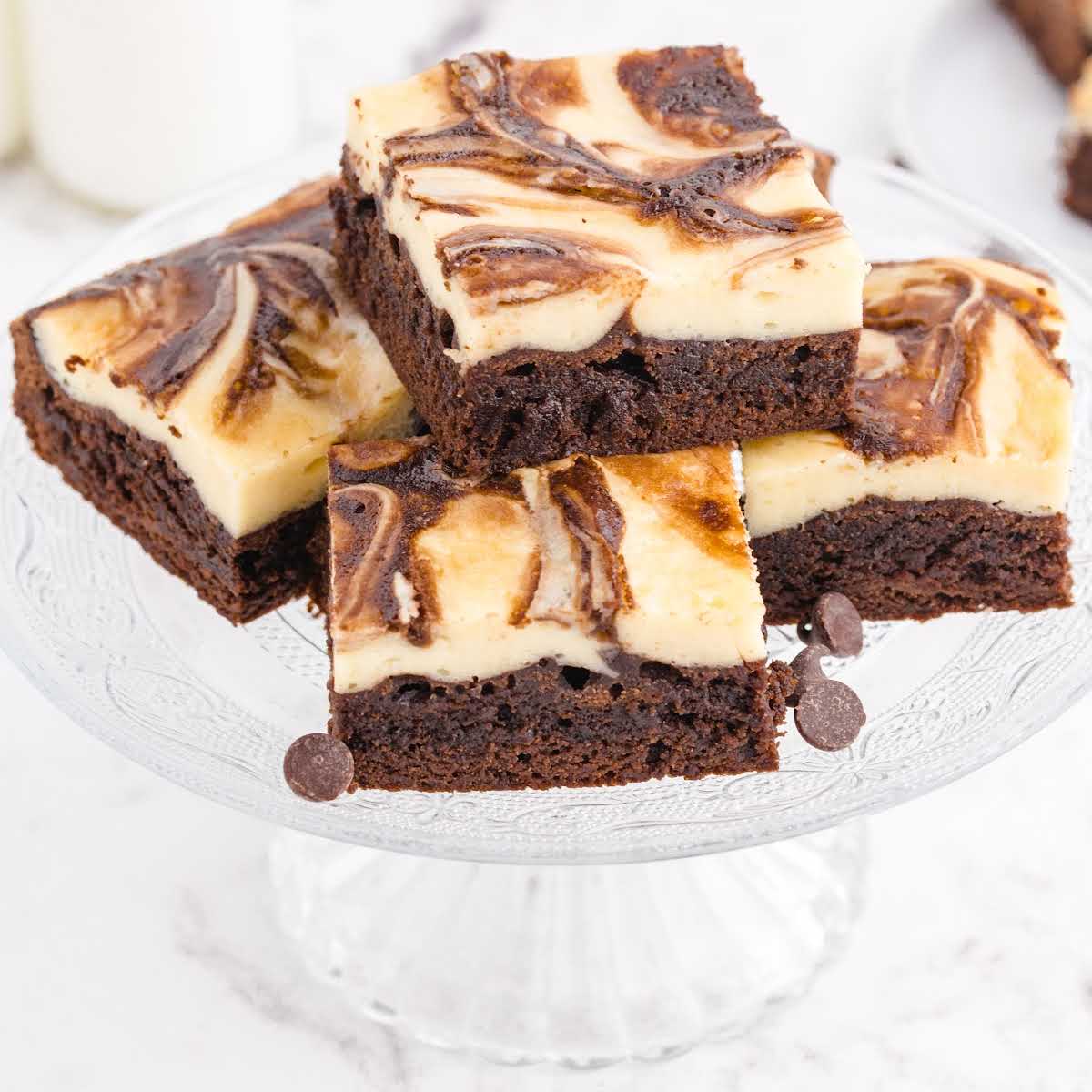 close up shot of Cheesecake Brownies stacked on top of each other on a serving plate