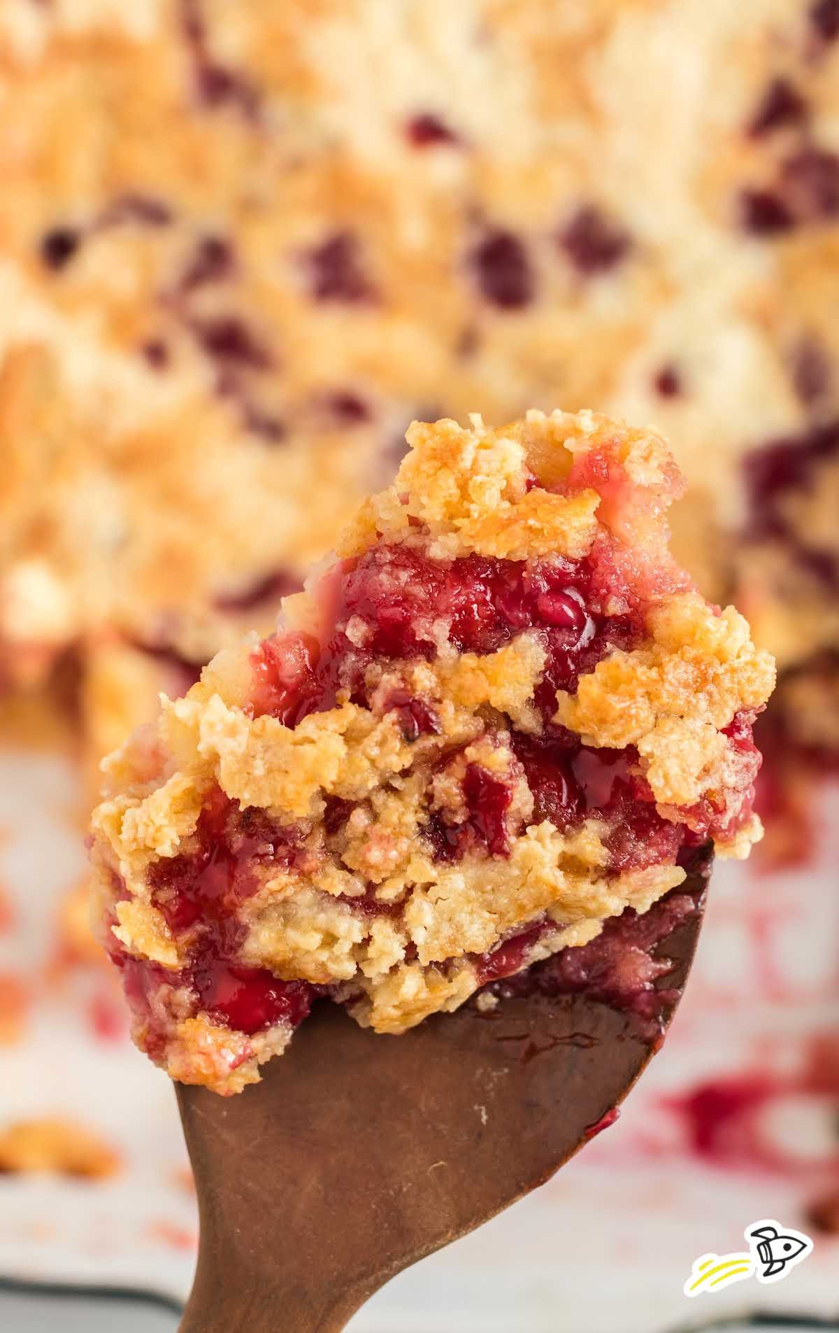 close up shot of Cherry Pineapple Dump Cake on a large wooden spoon