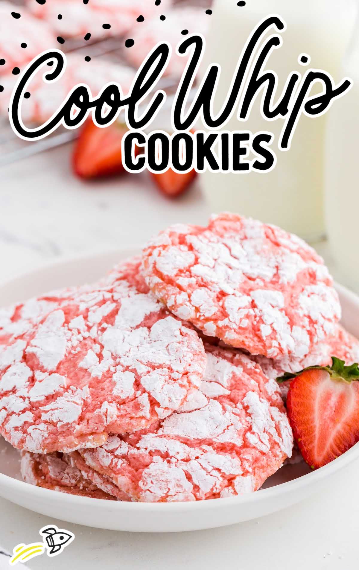 Cool Whip Cookies piled on a plate with a slice of strawberries