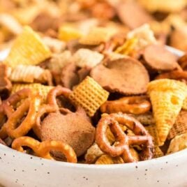 close up shot of a bowl of Crockpot Chex Mix surrounded by Crockpot Chex Mix