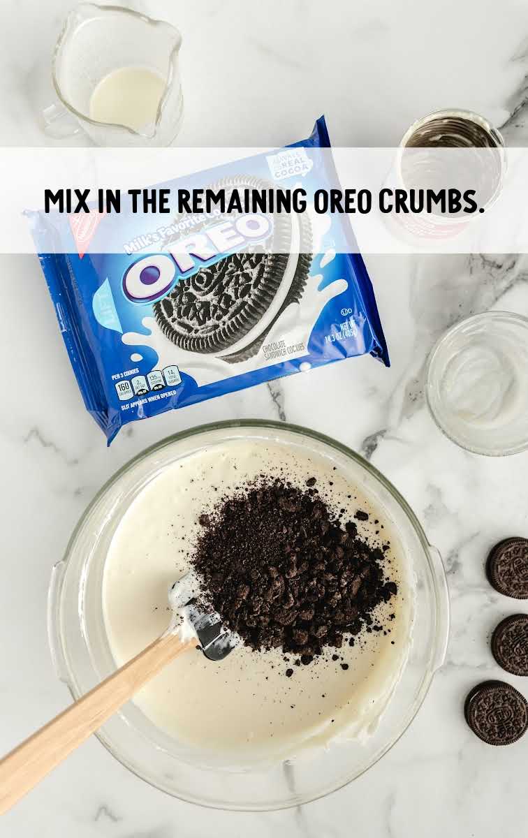Easy Frozen Oreo Dessert process shot of oreo crumbs being added to bowl of ingredients