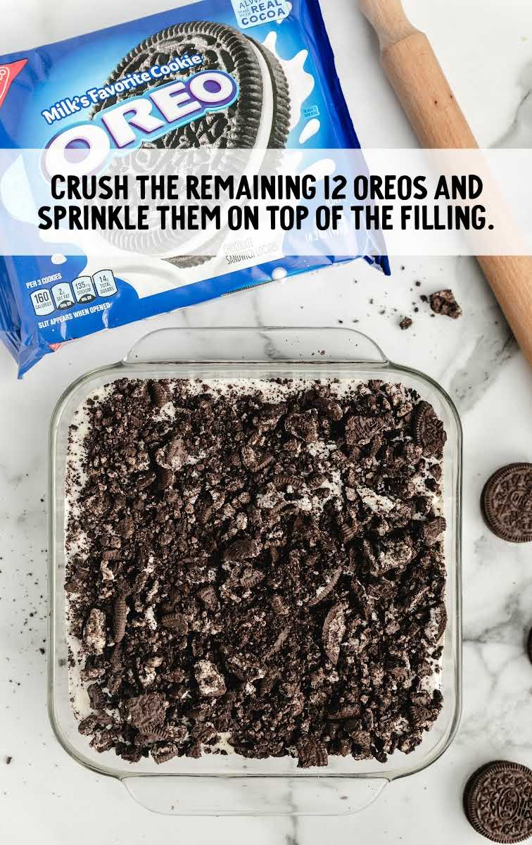 Easy Frozen Oreo Dessert process shot of crushed oreos being sprinkled on top of the dessert