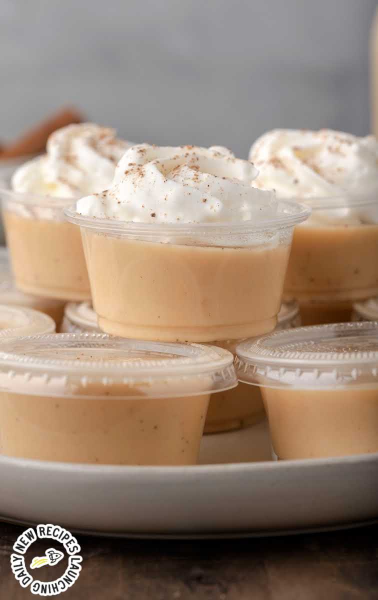 close up shot of containers of Eggnog Jello Shots topped with whipped cream and sprinkled with nutmeg on a plate