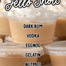 close up shot of containers of Eggnog Jello Shots topped with whipped cream and sprinkled with nutmeg on a plate