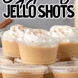 containers of Eggnog Jello Shots topped with whipped cream and sprinkled with nutmeg on a plate
