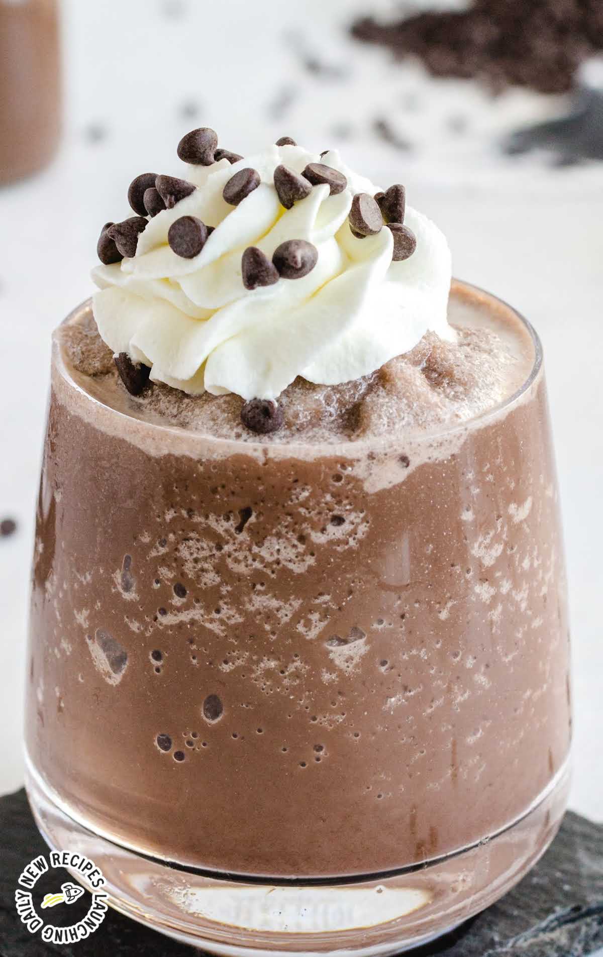 close up shot of a glass of Frozen Hot Chocolate topped with whipped cream and mini chocolate chips