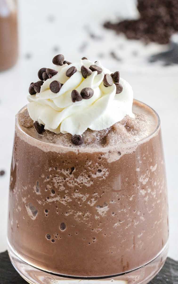 close up shot of a glass of Frozen Hot Chocolate topped with whipped cream and mini chocolate chips