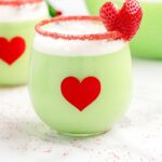 close up shot of a glass of Grinch Punch garnished with a cut out heart strawberry