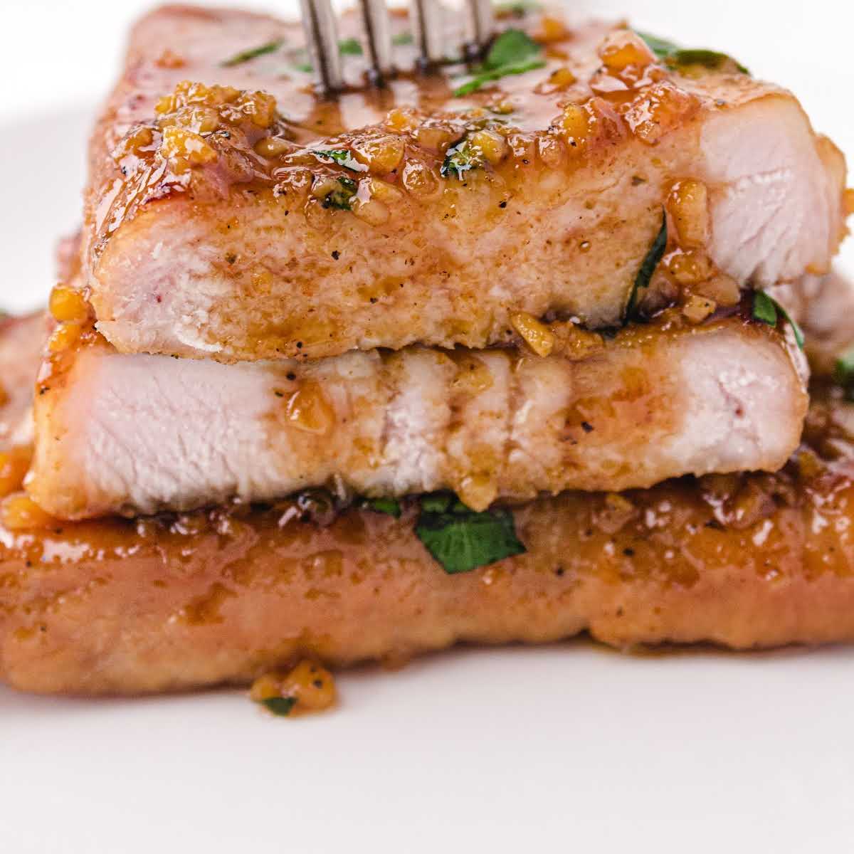 close up shot of Honey Garlic Pork Chops garnished with parsley and stacked on top of each other