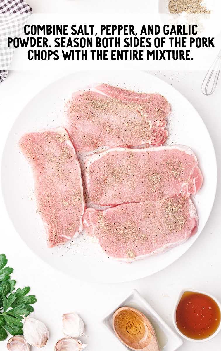 pork chops being seasoned on a plate