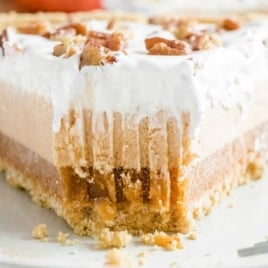 Overhead view of a sliced layered pumpkin spice Jello pie with whipped topping and a graham cracker crust.
