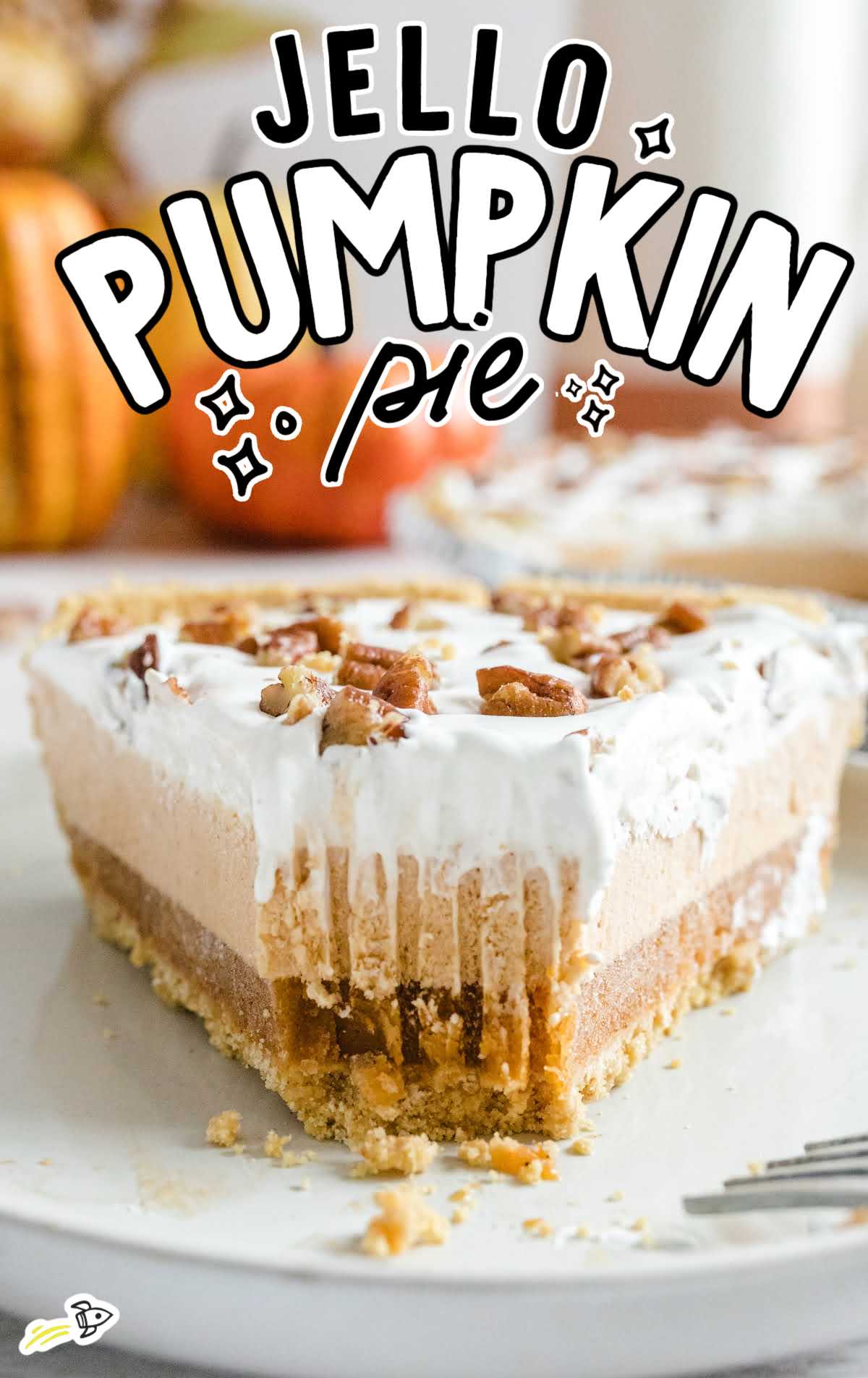 Close-up of a slice of layered pumpkin spice Jello pie with whipped topping and chopped pecans on top, showing creamy layers and graham cracker crust.