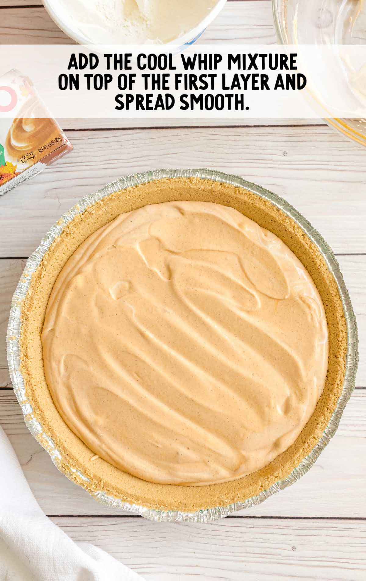 Final whipped topping layer being spread over the chilled pumpkin spice Jello pie.