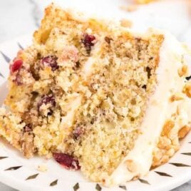 close up shot of a slice of Orange Cranberry Cake garnished with chopped walnuts on a plate