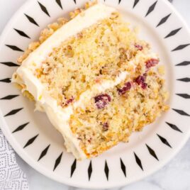 close up overhead shot of a slice of Orange Cranberry Cake garnished with chopped walnuts on a plate