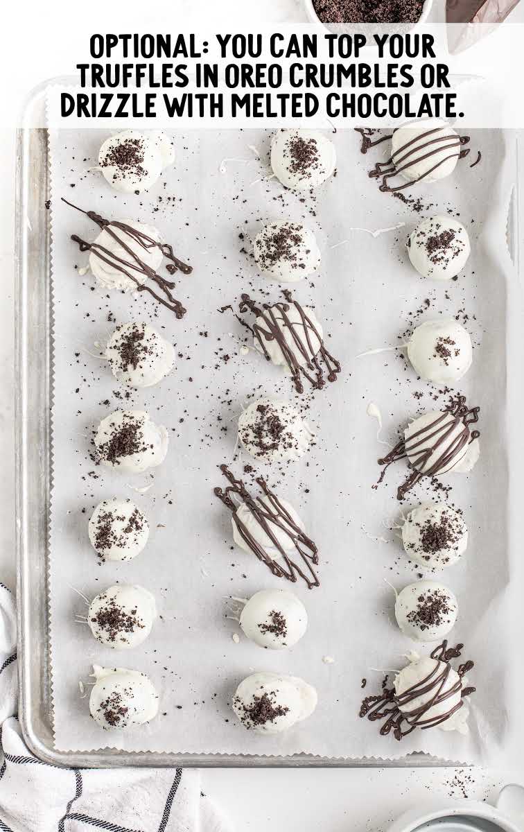truffles being garnished with oreo crumbles or melted chocolate on a sheet pan
