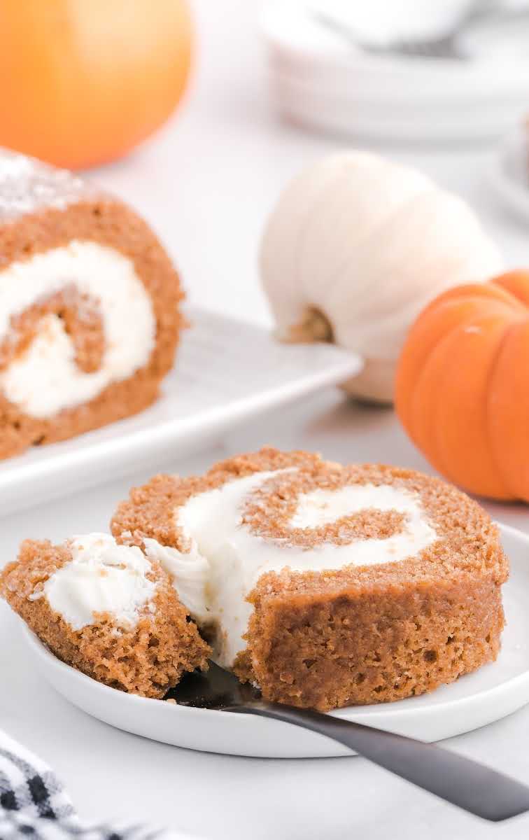 close up shot of a slice of Pumpkin Roll on a plate with a fork