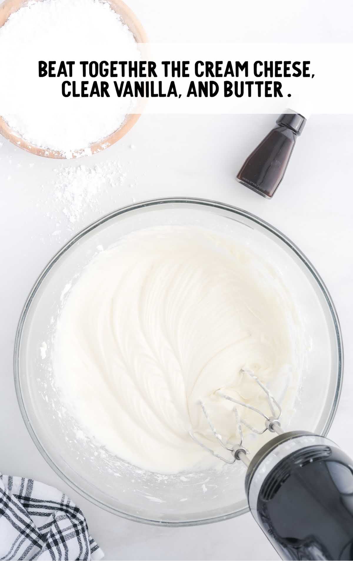 cream cheese, vanilla, and butter being whisked together in a bowl