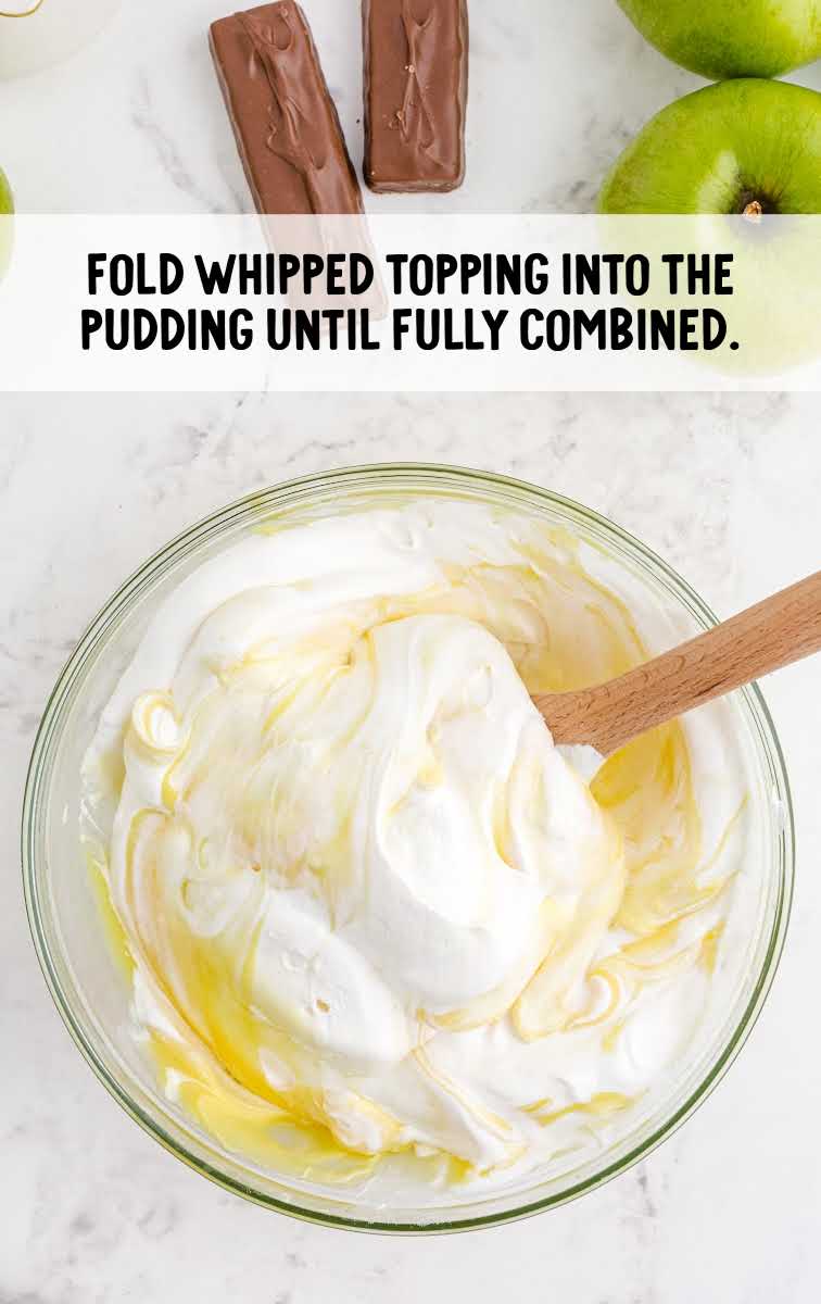 cool whip being combined into the ingredients in a bowl