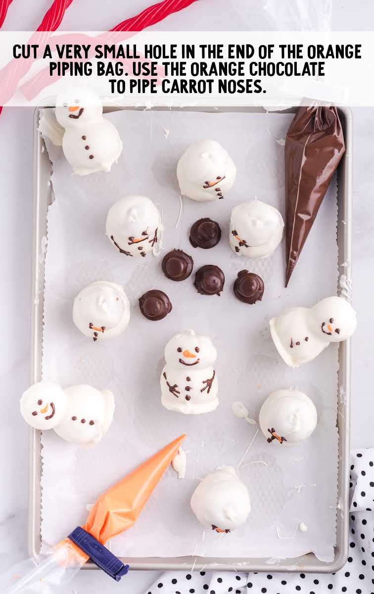 snowmen truffles process shot of nose placed on snowmen with a piping bag of orange chocolate