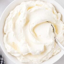close up overhead shot of a bowl of stabilized whipped cream with a spoon