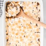 close up overhead shot of Sweet Potato Casserole in a baking dish with a large wooden spoon