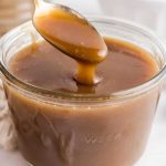 close up shot of a jar of Toffee Sauce with a spoon dipped into the jar