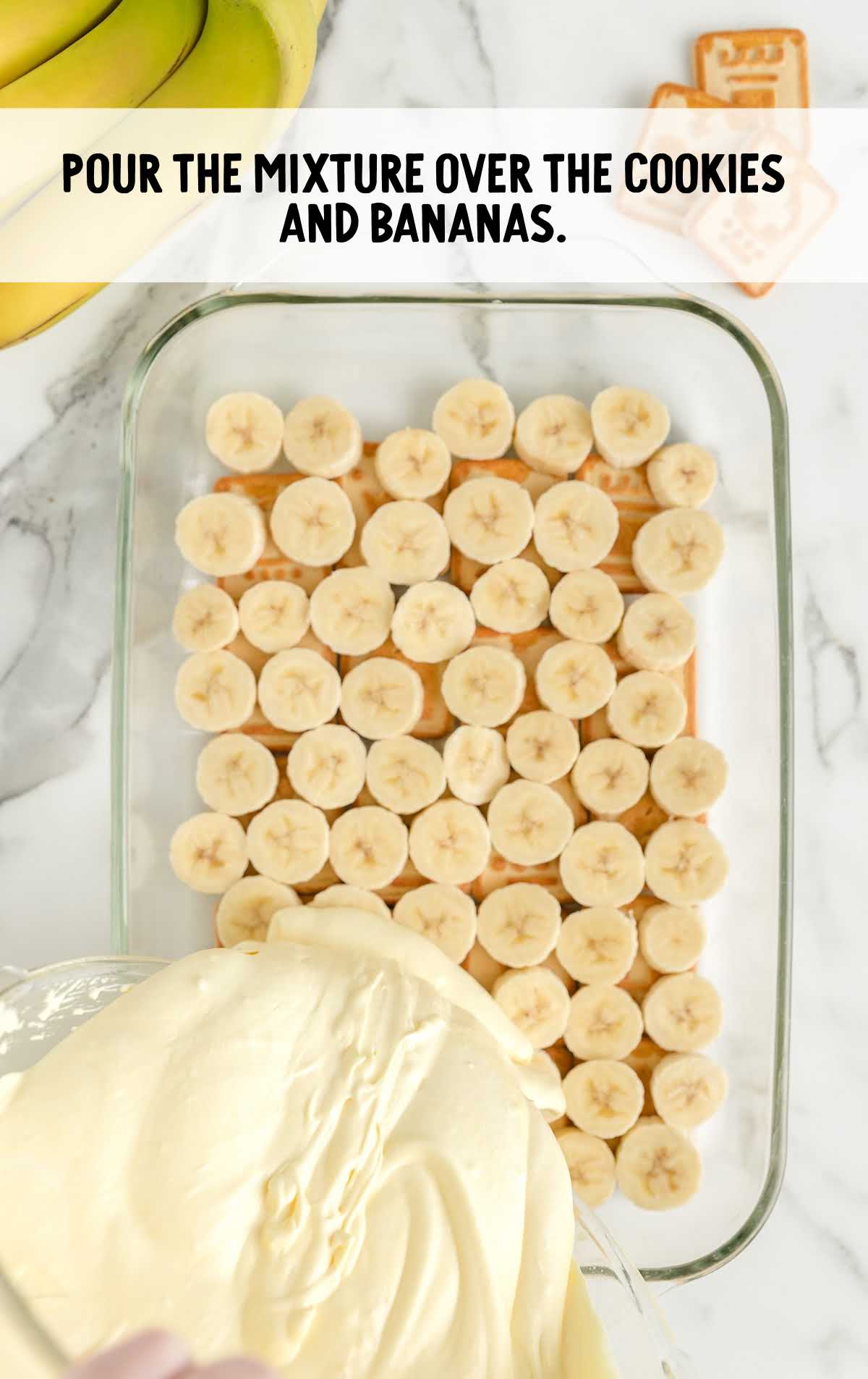 Pouring pudding mixture over sliced bananas and cookies in a glass dish to assemble chessmen banana pudding.
