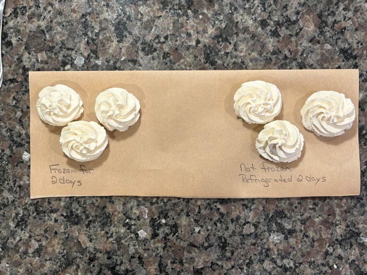 Six piped whipped cream swirls are placed on brown paper over a granite counter. Three on the left use a Stabilized Whipped Cream Recipe and are labeled Frozen for 2 days; the other three are Not frozen, Refrigerated 2 days, like Homemade Cool Whip.