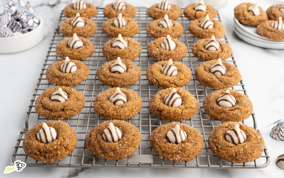 Gingerbread kiss cookies arranged on a cooling rack with Hershey’s Hugs pressed into the center.