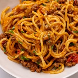 A close-up of a plate of Taco Spaghetti, featuring ground beef, tomato sauce, melted cheese, and chopped parsley. This Taco Spaghetti recipe looks hearty and flavorful, with ingredients evenly combined for a tasty twist on a classic dish.