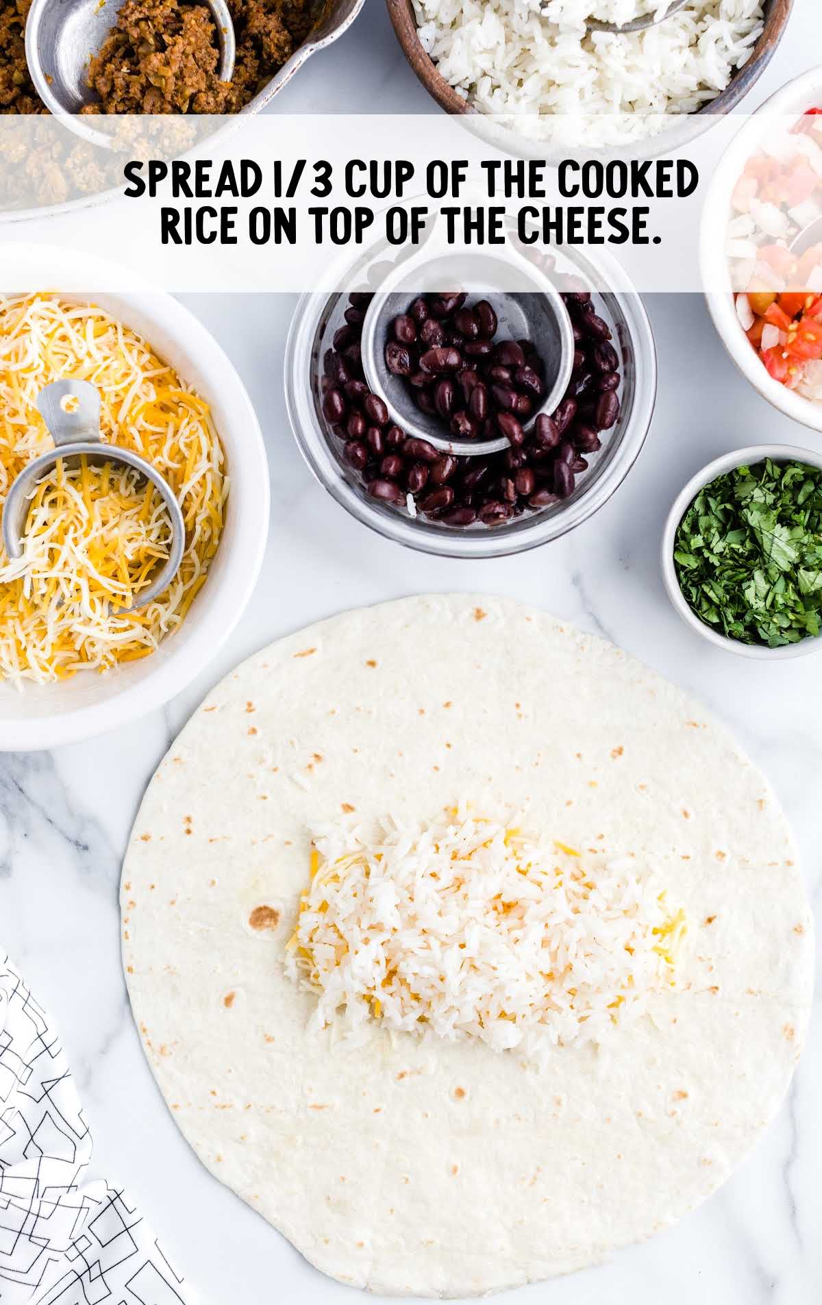 white rice being placed on top of the shredded cheese on the tortilla