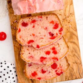 close up overhead shot of a loaf of Cherry Bread with pieces of bread sliced off on a wooden board