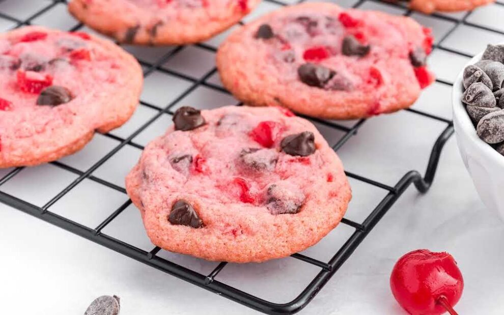 close up shot of Cherry Chocolate Chip Cookies on a cooling rack with a bowl of chocolate chips on the side