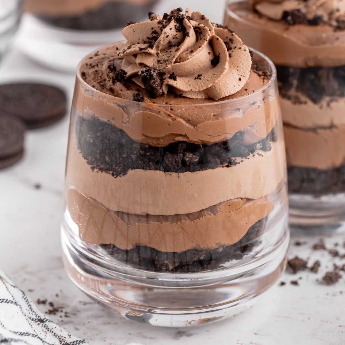 close up shot of glasses of Bailey's Chocolate Cheesecake Trifle topped with whipped cream and sprinkled with cookie crumbles