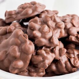 close up shot of Chocolate Peanut Clusters piled on top of each other in a bowl