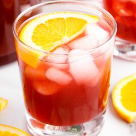 close up shot of a glass of Christmas Morning Punch garnished with a orange slice