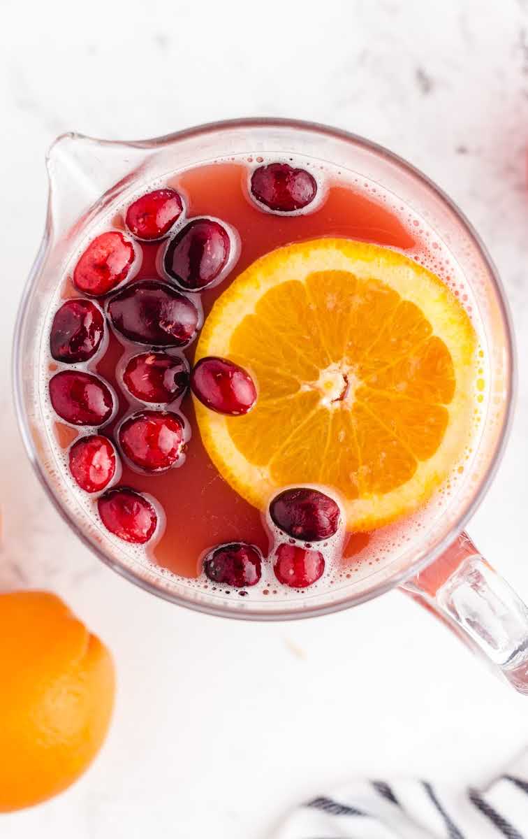 close up overhead shot a pitcher of Christmas Punch garnished with cranberries and a orange slice