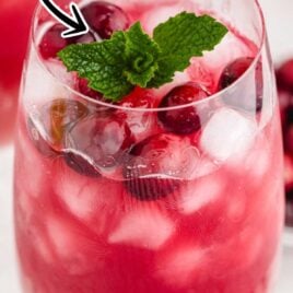close up shot of a glass of Christmas Punch garnished with cranberries and a mint