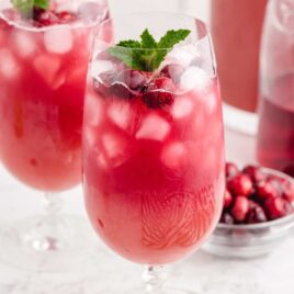 close up shot of glasses of Christmas Punch garnished with cranberries and a mint