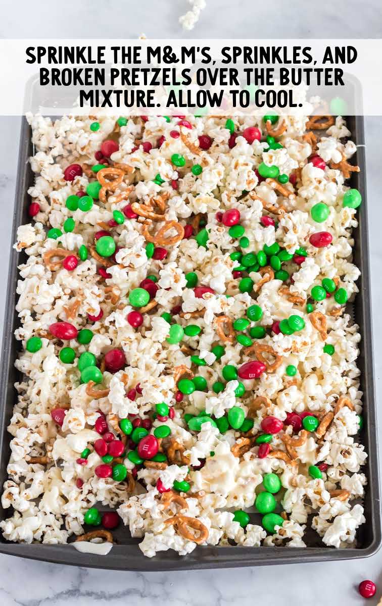 Christmas crunch process shot of m&m's, sprinkles, and broken pretzels sprinkled on top of popcorn