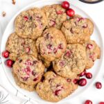 close up overhead shot of a plate piled with Cranberry Pecan Oatmeal Cookies and garnished with cranberries