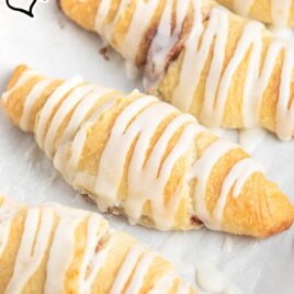 close up shot of a baking sheet of Crescent Roll Cinnamon Rolls drizzled with glaze
