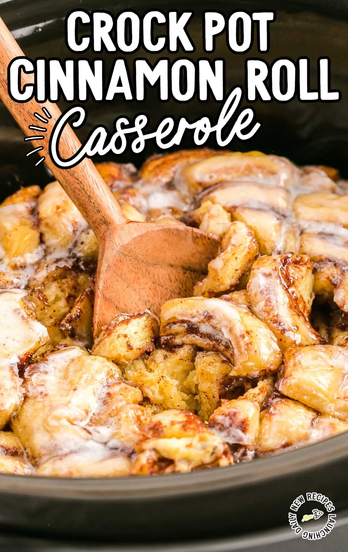 close up shot of  Cinnamon Roll Casserole in a crockpot with a large wooden spoon